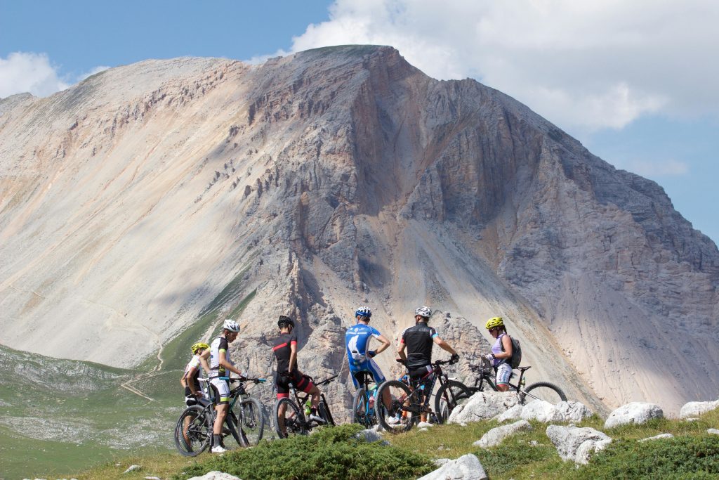 Group of cyclists mountain biking in the scenic Dolomites, Italy on a sunny day.