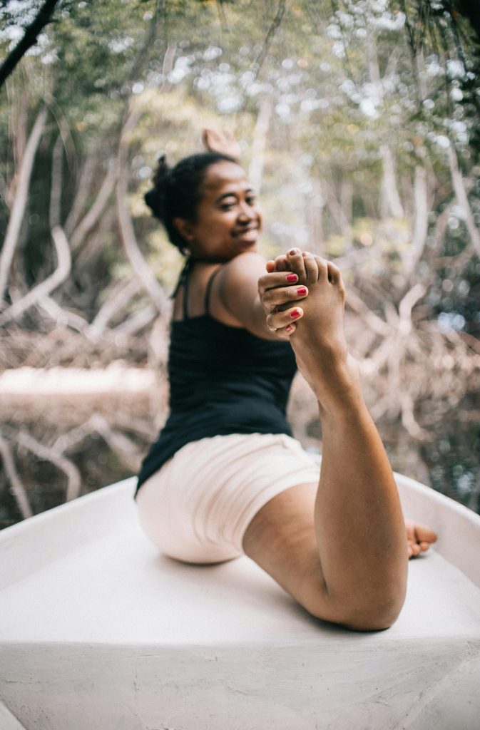 A woman exercises outdoors on a boat, showcasing flexibility in a peaceful natural setting.